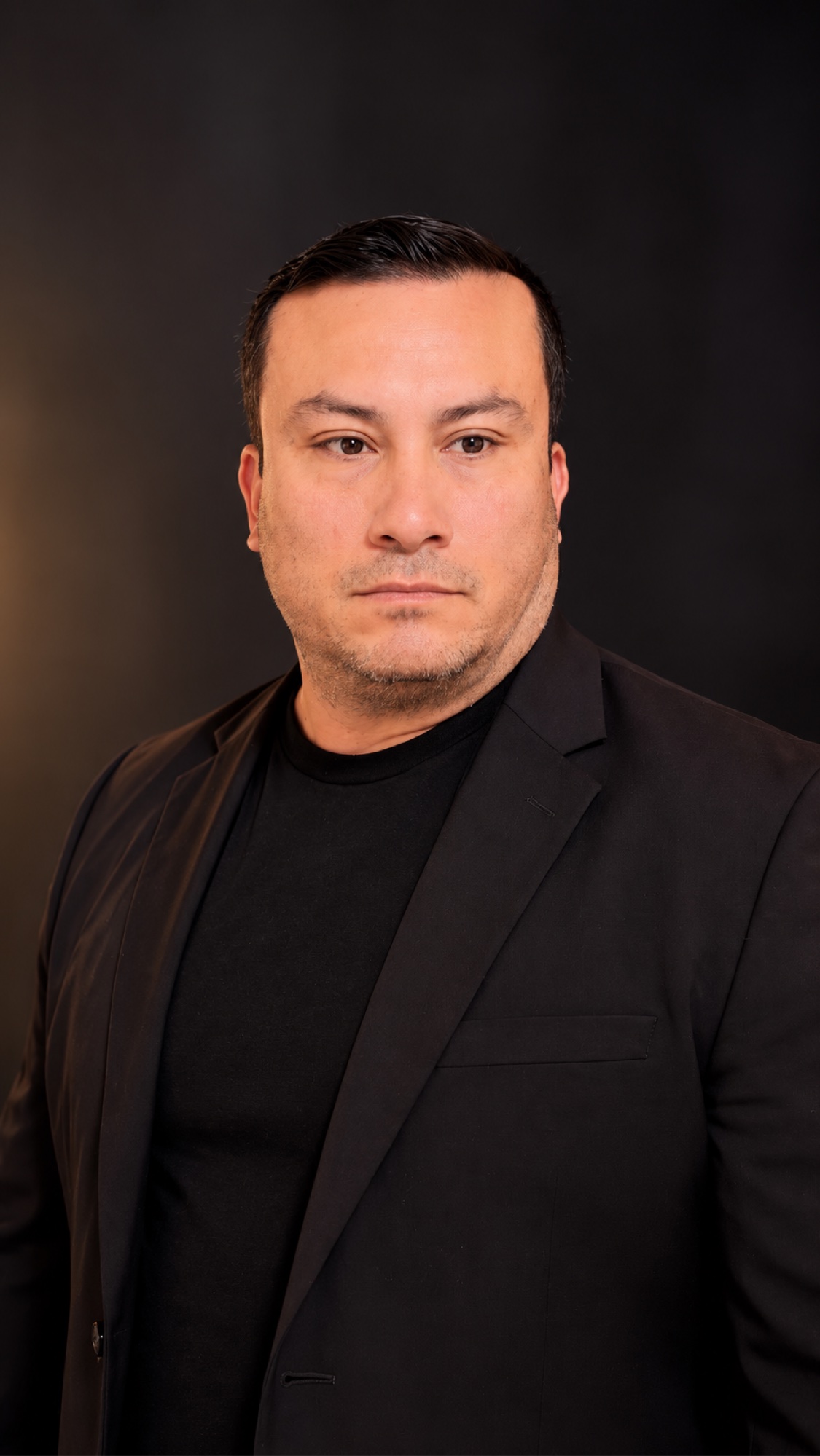 SHINNO wearing a black blazer in a studio portrait