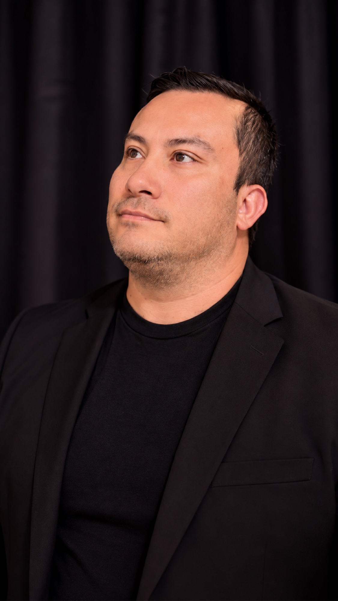 SHINNO in profile wearing a black blazer