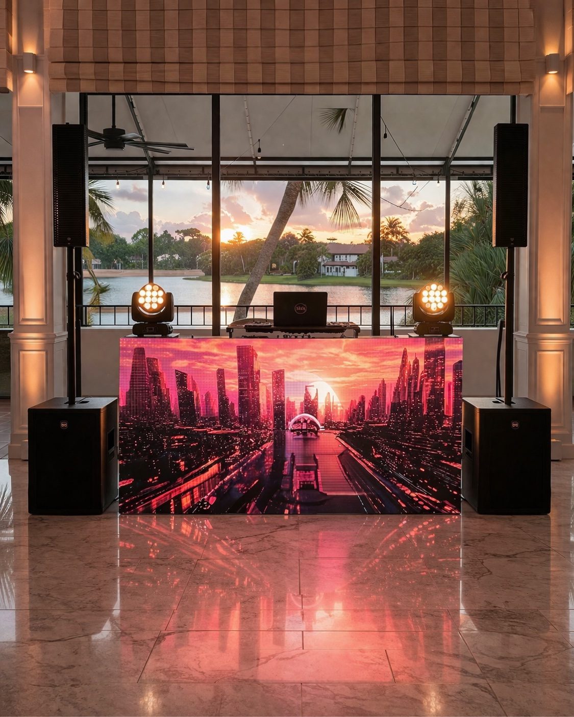 DJ booth with cityscape LED visuals overlooking a sunset lake