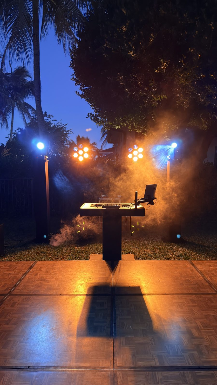 Outdoor night DJ setup with smoke and moving head lights