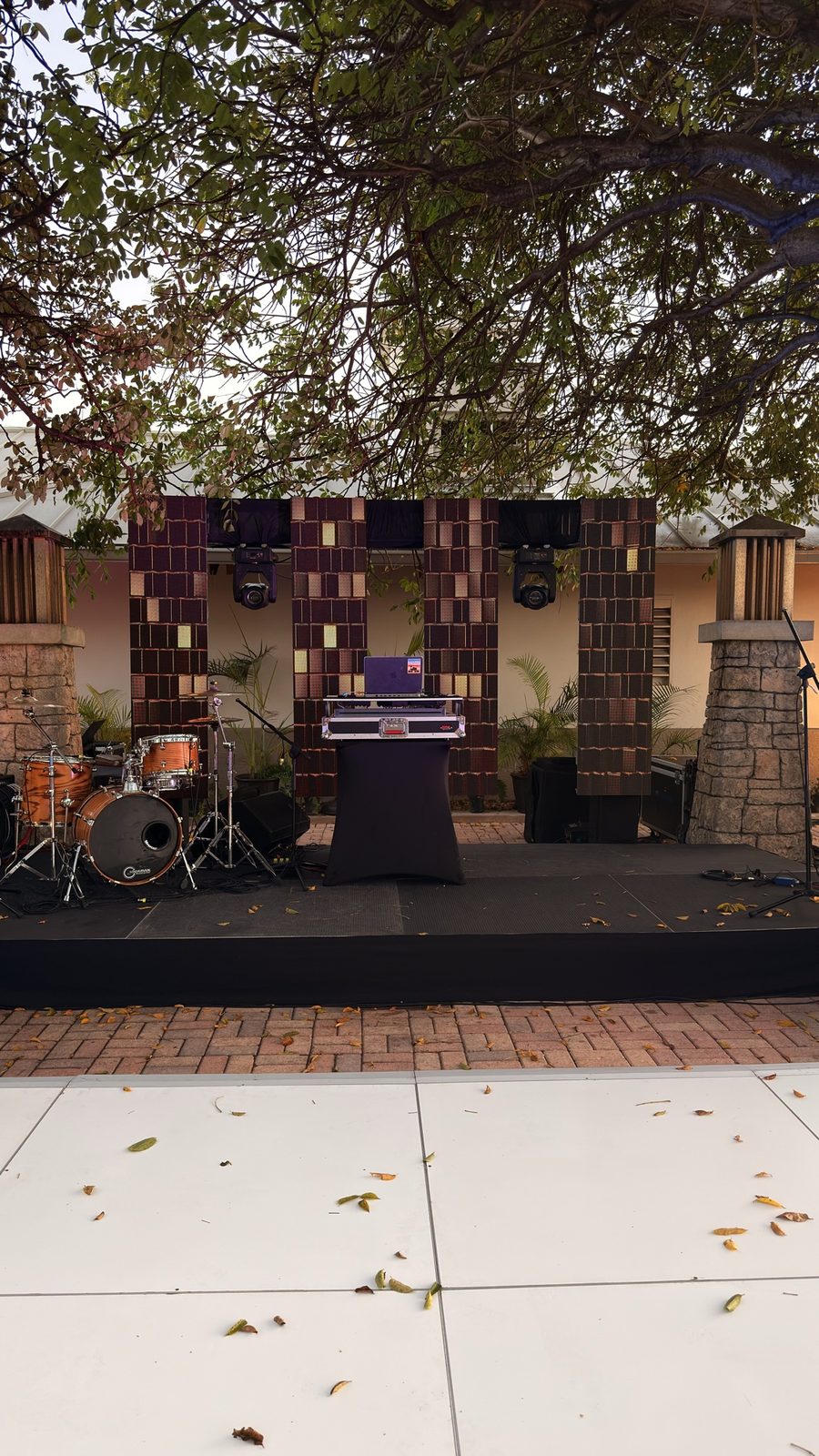 Outdoor DJ stage with drums under a large tree
